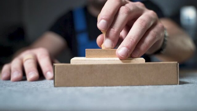 Worker in overalls labeling a cardboard package with a wooden stamp.
