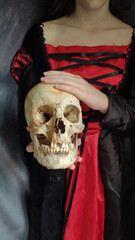 Human skull in the hands of a girl in a gothic dress. Death. Teaching about death. Philosophy.
