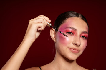 Fototapeta premium pretty woman Makeup Brush clean leather bright makeup posing pink background unaltered