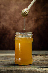 Honey jar and wooden spoon in jar. Bees produce fresh, healthy, honey. Honey background. Beekeeping concept
