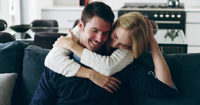 Generous with their affection. Happy young couple sharing an affectionate moment at home on the sofa. Young woman affectionately kissing her boyfriend and bonding with him in the lounge