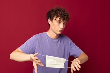 A young man medical mask protection posing red background unaltered