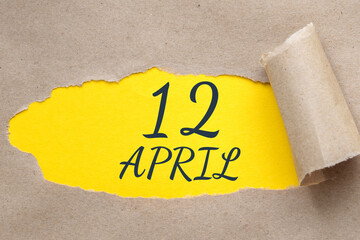 April 12. 12th day of the month, calendar date.Hole in paper with edges torn off. Yellow background is visible through ragged hole.Spring month, day of the year concept