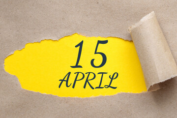 April 15. 15th day of the month, calendar date.Hole in paper with edges torn off. Yellow background is visible through ragged hole.Spring month, day of the year concept