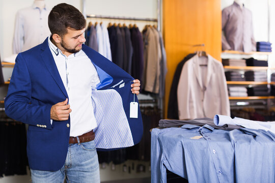 Male customer choosing jacket in men clothes shop