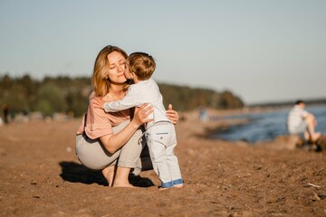 Fototapeta na wymiar cute little caucasian boy kissing his young mother at the beach
