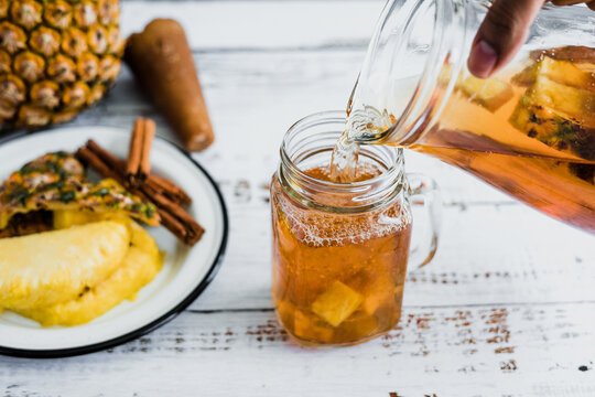 Tepache mexican Fermented pineapple drink and hand holding a Jar with kombucha homemade probiotic superfood sliced pineapple beverage in Mexico city	