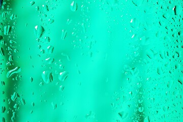 Water droplets on green background transparent glass surface