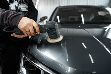 Obraz na płótnie Canvas Car detailing. Male hands with orbital polisher in auto repair shop