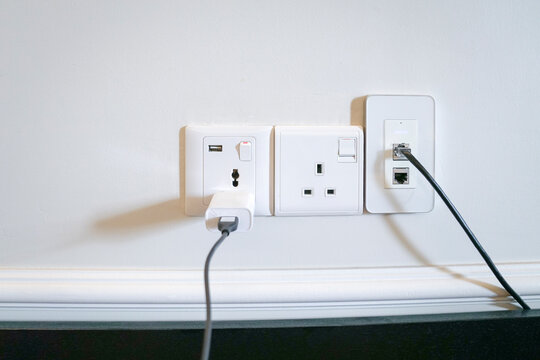 Electric power outlets on the wall with data and charging cable connected.