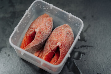 Top view of Fresh frozen raw red salmon fish. Frozen salmon steaks in a plastic box or container