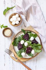 Healthy diet salad with arugula, spinach, beetroot, mozzarella and vinaigrette dressing on a wooden...