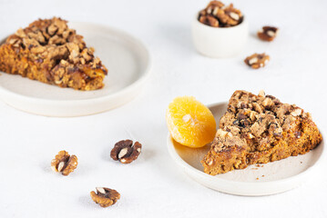 Pieces of homemade tangerine pie with nuts in plates on a light table. Healthy food, sugar, gluten and lactose free, vegan.