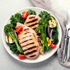 Grilled chicken with vegetables on light background.
