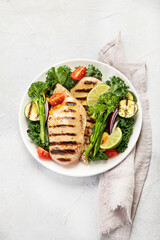 Grilled chicken with vegetables on light background.