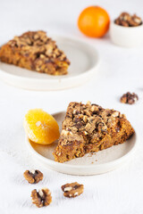 Pieces of vegan homemade tangerine pie with nuts in plates on a light table. Healthy food, sugar, gluten and lactose free.