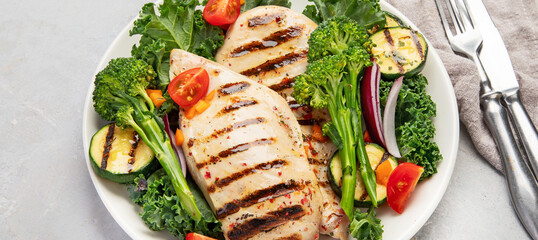 Grilled chicken with vegetables on light background.