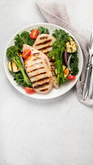 Grilled chicken with vegetables on light background.
