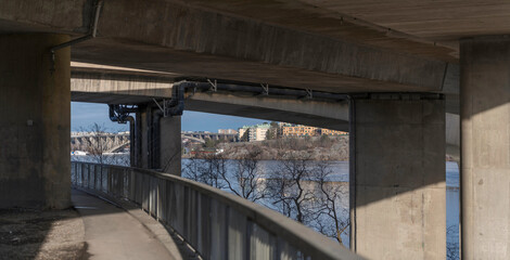 Path way and foundation of and bridges parts of the high way Essingeleden through Stockholm at the lake Mälaren, skyline with functionalist houses on a cliff a cold sunny winter day in Stockholm