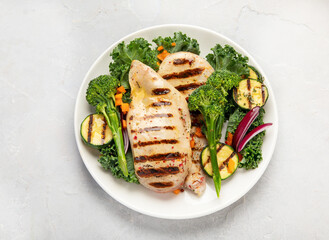 Grilled chicken with vegetables on light background.