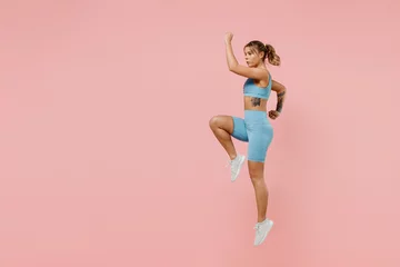 Foto op Plexiglas anti-reflex Full body young strong sporty athletic fitness trainer instructor woman 20s wear blue tracksuit spend time in home gym jump high run isolated on pastel plain pink background. Workout sport concept © ViDi Studio