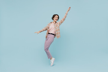 Obraz premium Full body young smiling happy woman 20s wearing casual brown shirt stand on toes dance leaning back fooling around isolated on pastel plain light blue color background studio People lifestyle concept
