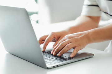 Close up of woman hands typing on laptop keyboard on the table at home office or workplace.