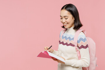 Smart teen student girl of Asian ethnicity wear sweater backpack hold books write down lesson in...