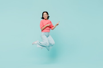 Fototapeta na wymiar Full body young smiling happy woman of Asian ethnicity 20s wear pink sweater jump high point index finger camera on you isolated on pastel plain light blue background studio. People lifestyle concept.