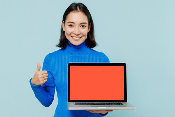 Young woman of Asian ethnicity 20s wears blue shirt use laptop pc computer with blank screen...