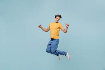Full body overjoyed excited fun cool young man 20s wear yellow t-shirt jump high do winner gesture...