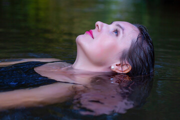 mystical woman in black dress splashes in the river