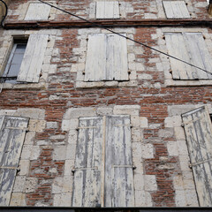 Old abandoned house white wooden shutters ancient in brick wall