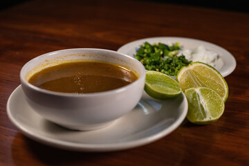 Mexican jugo de carne next to onion and cilantro plate