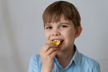 Close up portrait cheerful child having fun eating potato chips isolated on gray background. Cute...