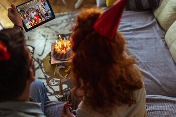 Young couple celebrating birthday online with cake.