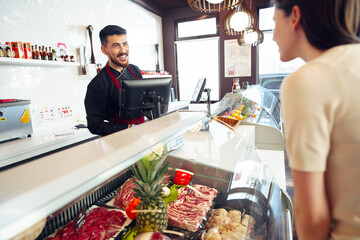 Female customer against raw meat stall section in food store