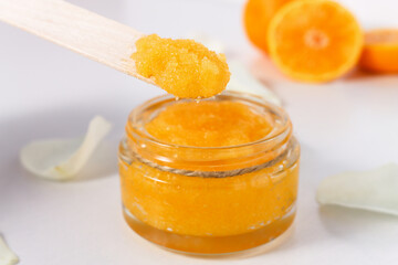 Container with sugar scrub and oranges for spa treatments. Cleanser for relaxing and exfoliating...