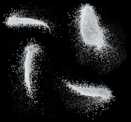 White refined sugar crystals falling down at black background.