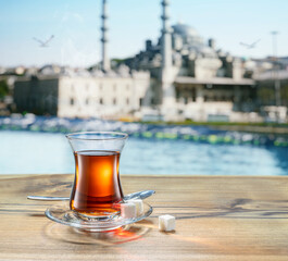Turkish tea served in tulip-shaped glass on a small saucer blurred  old town and sea at the background.