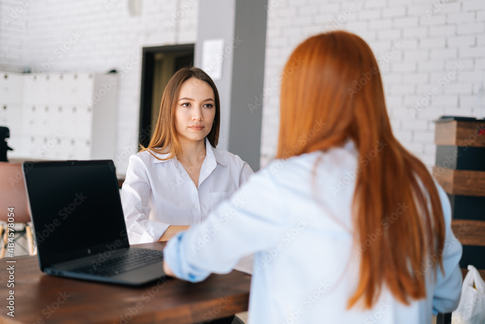 Wall mural back view of two serious focused young business women discussing new project sharing ideas sitting a