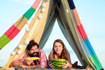 Fototapeta premium Romantic couple eat watermelon in tent on camping. Outdoor adventure with friends on nature. Organic food.