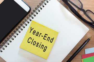 Text on yellow note with notepad on wooden desk - Year-end closing