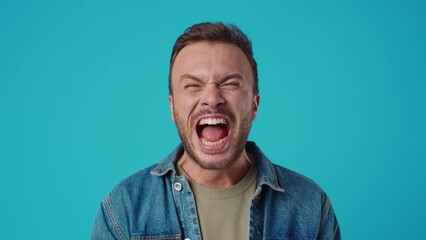 Angry young man shouting against blue background