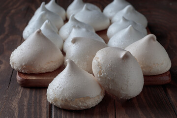 Close-up view of white sweet meringue on cooking board on wooden background. Selective focus.