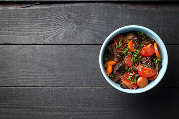 Plate with beef with vegetables on wooden background