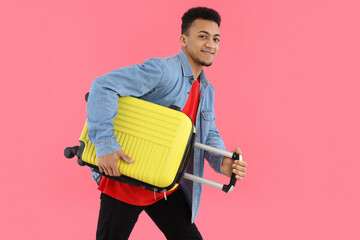 Young man with luggage bag on pink background