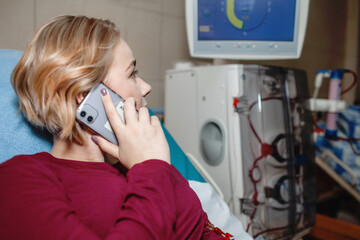Young beautiful girl, chatting with friends in social media during hemodialysis in hospital,...