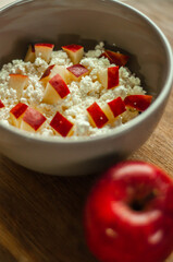 delicious and healthy breakfast homemade cottage cheese curd in a ceramic plate with red apple on wooden background, healthy food, dairy farm products, milk products