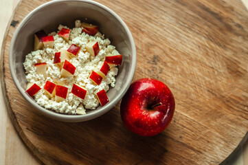 delicious and healthy breakfast homemade cottage cheese curd in a ceramic plate with red apple on wooden background, healthy food, dairy farm products, milk products